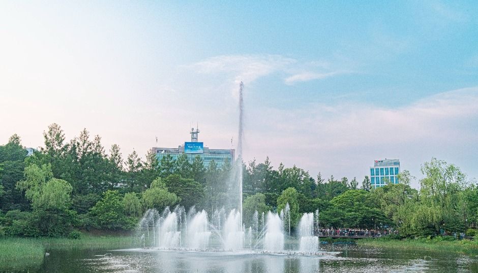 나무와 갈대 사이로 물줄기가 솟는 보라매공원 연못 분수