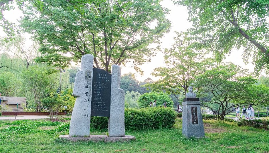 푸른 잔디와 나무 사이에 세워진 보라매공원 기념비