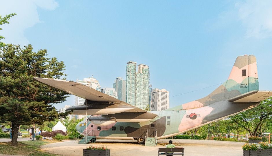 서울 도심의 나무와 고층 건물을 배경으로 전시된 보라매공원 퇴역 수송기