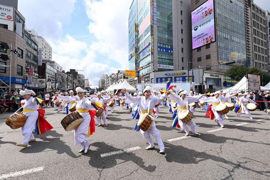 도심 도로에서 흰 한복을 입은 풍물패가 북과 장구를 치며 행진하는 부평풍물대축제 거리 행렬