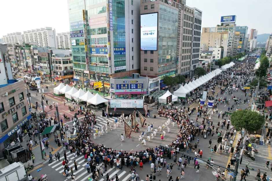 부평대로 사거리에서 풍물패가 원을 이루고 양옆으로 관람객과 천막이 늘어선 모습을 위에서 본 장면