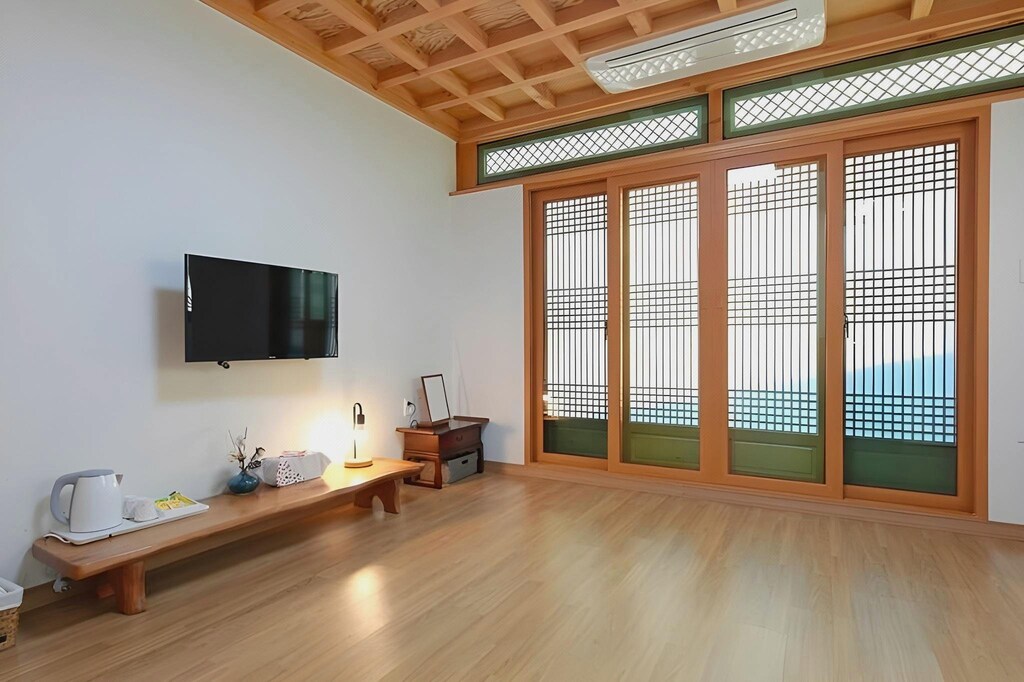한지 격자 창호 너머로 산과 하늘이 보이는 온돌 객실