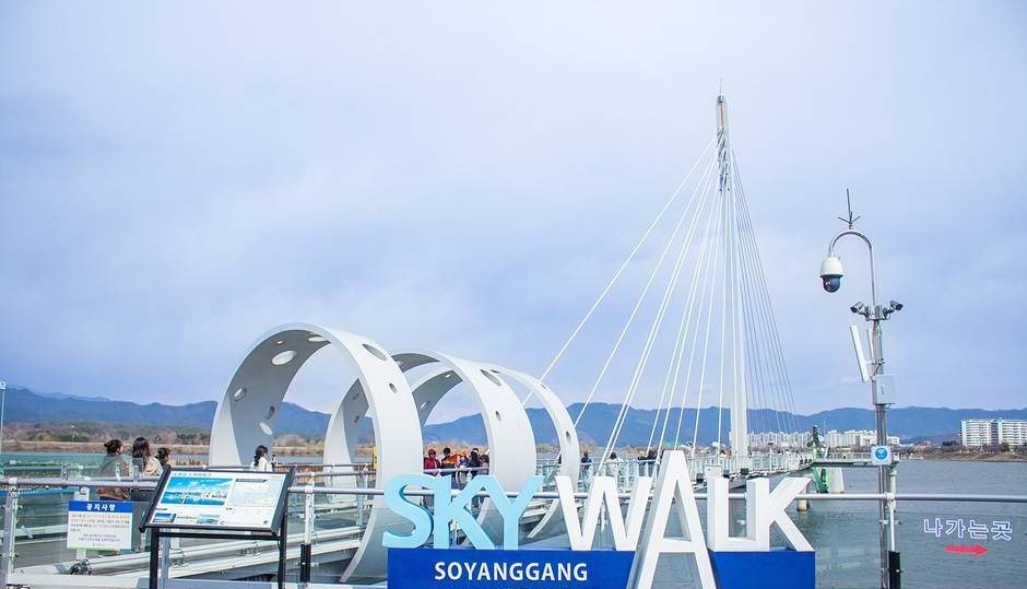 푸른 하늘 아래 SKYWALK 글자와 흰 아치가 보이는 춘천 소양강 스카이워크 입구