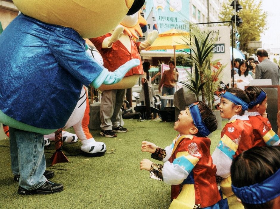 한복을 입은 아이들이 캐릭터 인형과 인사하며 놀고 있는 축제 체험 공간