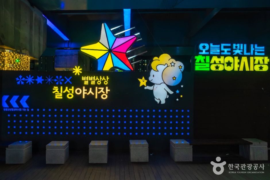 밤에 불이 켜진 칠성야시장 입구 조형물과 양 캐릭터