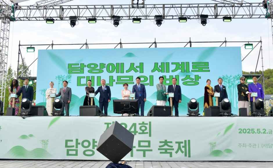 무대 위에 참석자들이 나란히 서서 대나무 모양 기념 조형물을 든 채 개막 세리머니를 하는 모습, 뒤로 축제 이름이 적힌 현수막