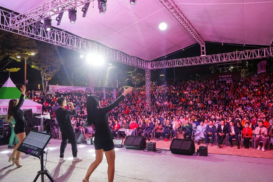 분홍빛 조명이 비추는 야외 무대 앞에 관객이 가득 모인 동래읍성 축제장
