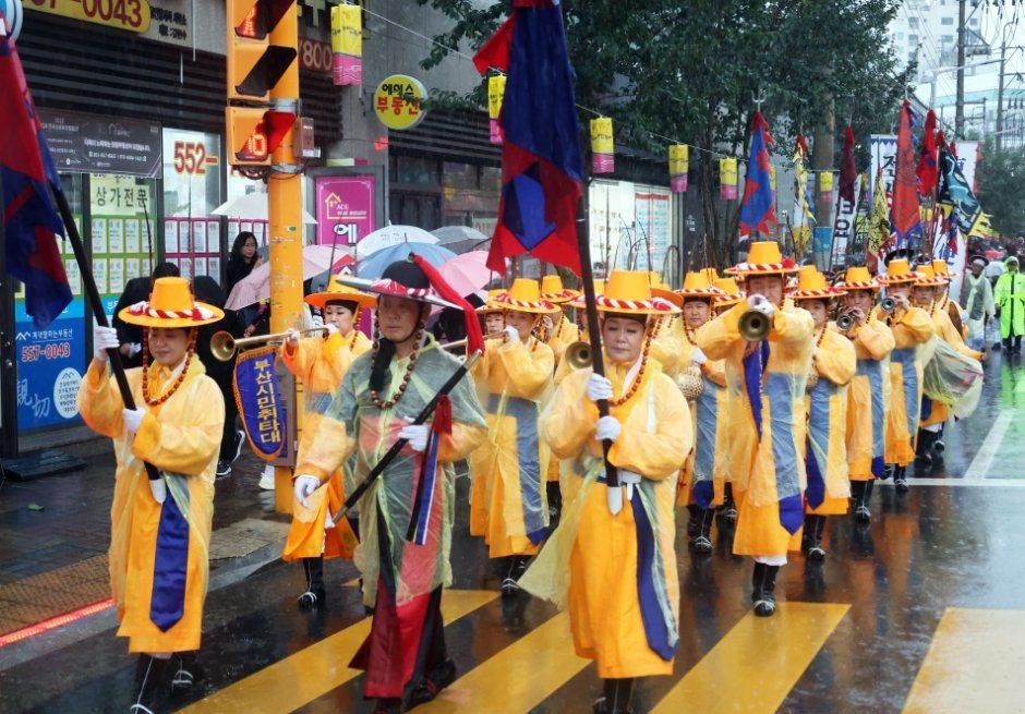노란 관복을 입은 행렬이 깃발을 들고 도로를 행진하는 동래읍성역사축제 길놀이
