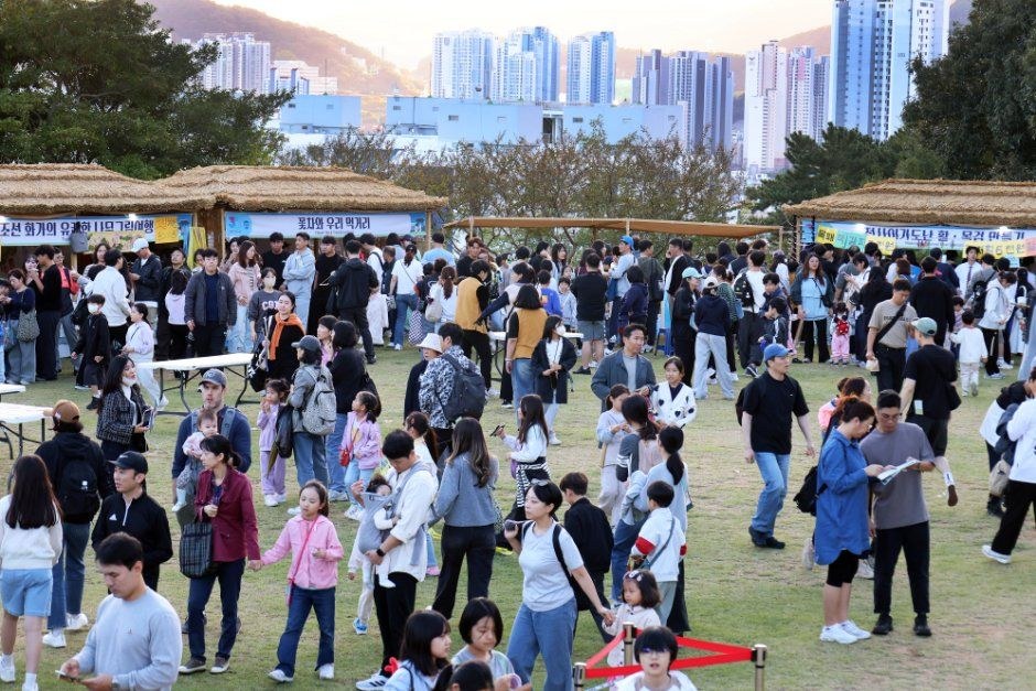 넓은 잔디 광장에 많은 방문객이 모여 천막 사이를 걷는 동래읍성 축제장