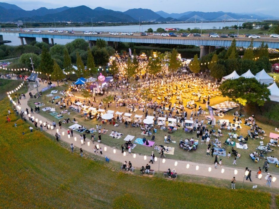 낙동강변 잔디밭에 수많은 방문객이 모여 천막과 야장이 이어진 구포나루 축제장 항공 전경