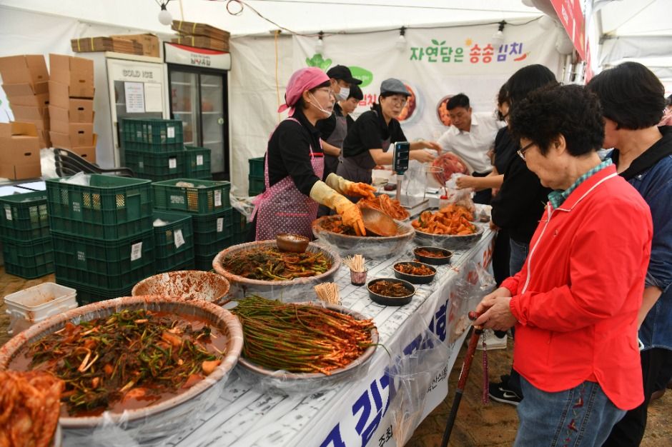 천막 아래 여러 종류의 김치가 담긴 큰 그릇들이 늘어선 시식·판매 부스와 줄 선 방문객
