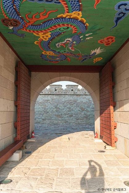 화려한 단청 용 그림이 그려진 경주읍성 성문 천장과 그 너머로 보이는 성곽