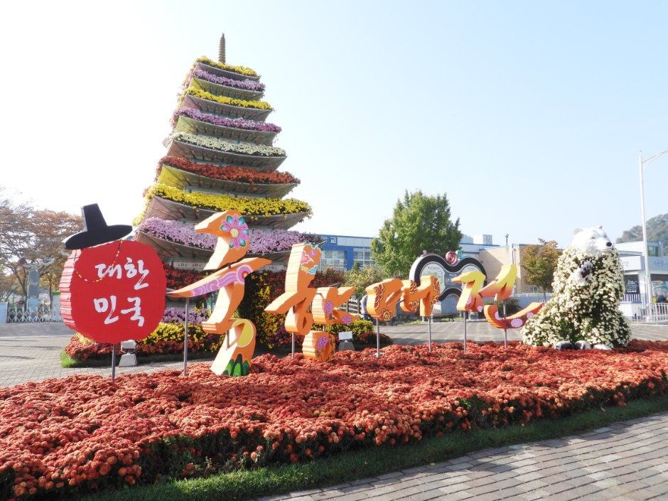 입구 근처에 국화로 쌓은 탑 모양 조형물과 대한민국 글씨가 보이는 함평 국향대전 광장