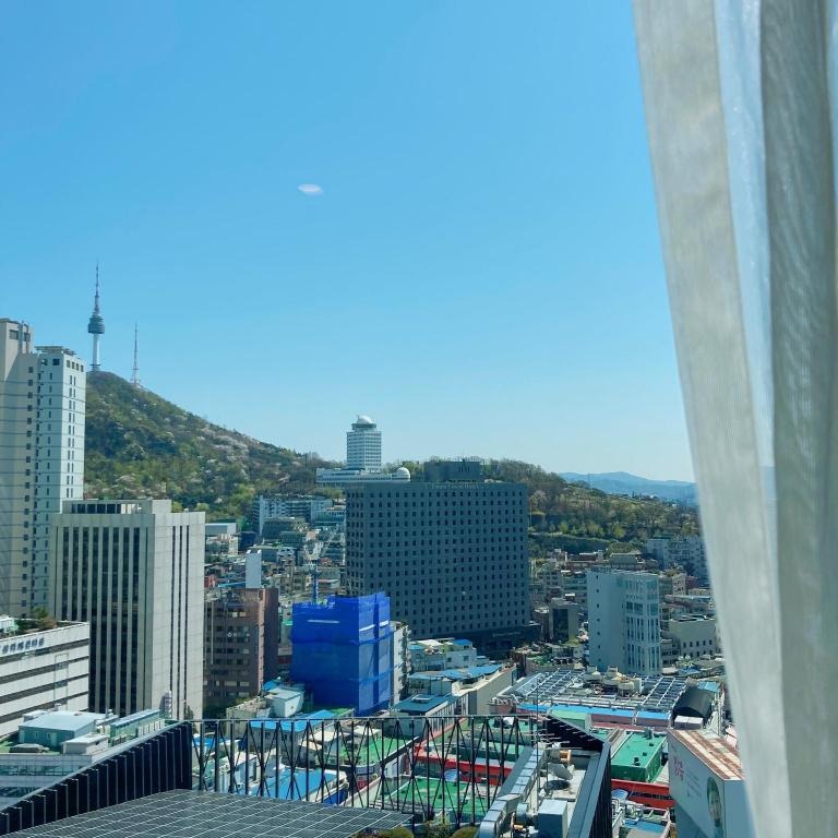 호텔 객실 창 너머로 남산과 서울 도심 건물이 보이는 전망