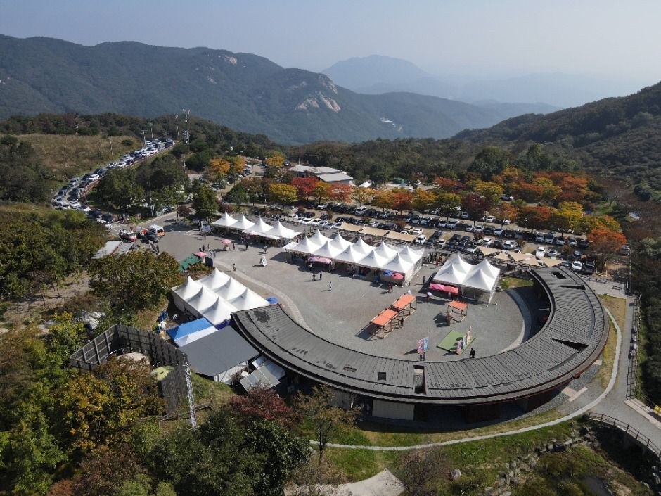 산봉우리 아래 원형 건물과 천막이 있는 황매산 광장을 위에서 본 모습