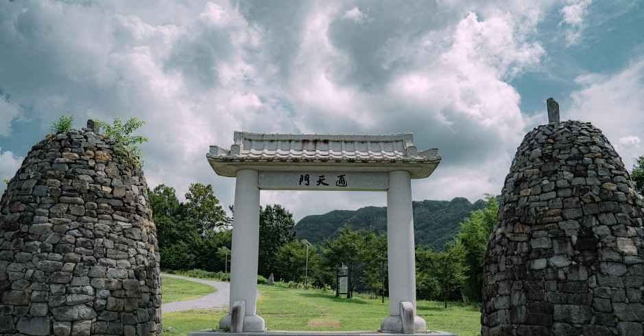 돌탑 두 개 사이에 서 있는 문과 뒤로 산이 보이는 적벽 유적