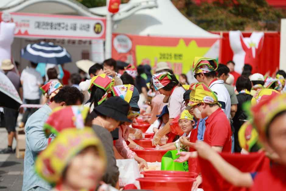 빨간 두건을 쓴 참가자들이 나란히 서서 홍삼깍두기 담그기 체험을 하는 모습