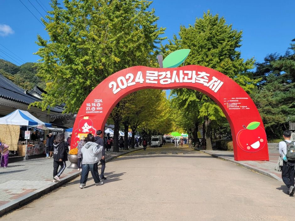 붉은 사과 모양 아치형 입구 조형물과 은행나무 단풍이 늘어선 문경새재 진입로