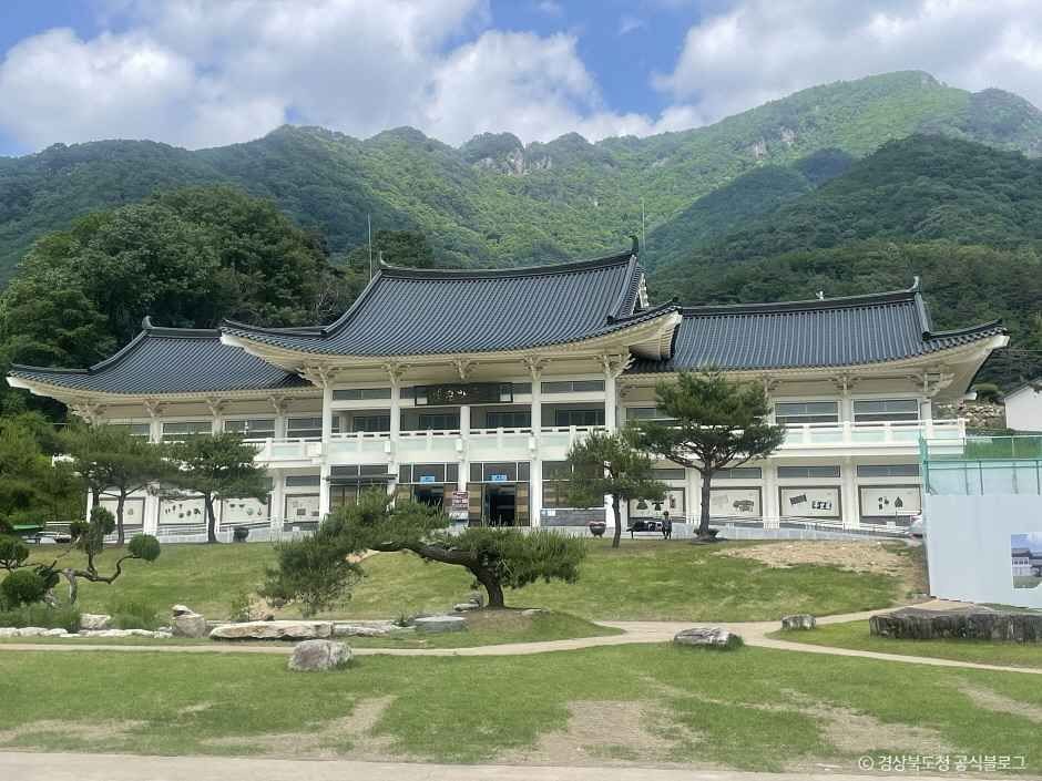 푸른 산을 배경으로 정원 앞에 한옥 건물이 서 있는 문경새재 일대