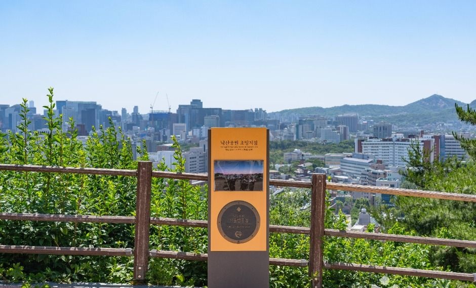 낙산공원 조망 안내판 뒤로 서울 도심 건물과 산 능선이 펼쳐지는 전망
