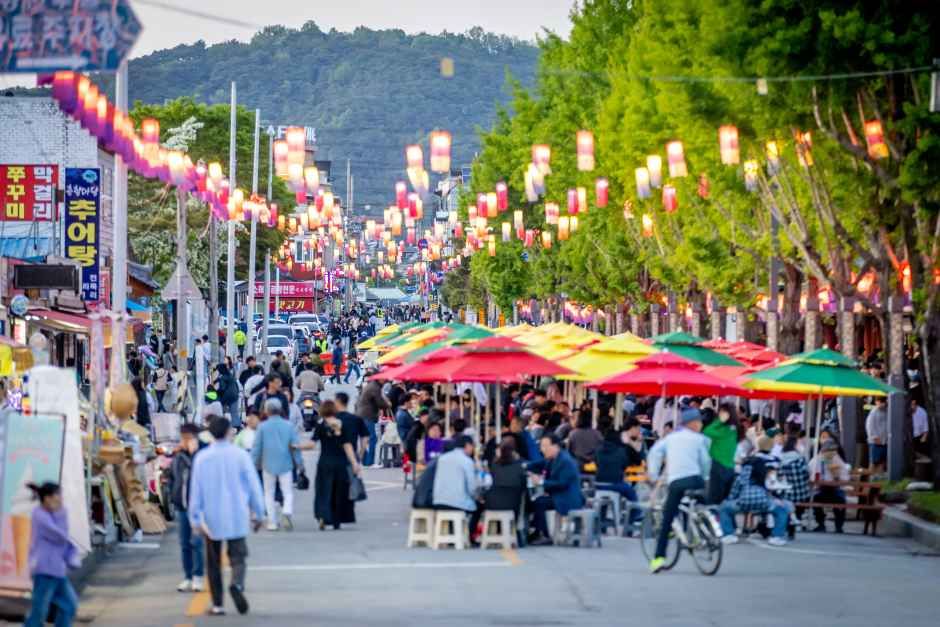 붉고 노란 청사초롱이 길게 늘어선 야간 거리를 방문객들이 걷고 있는 광한루원 인근 풍경