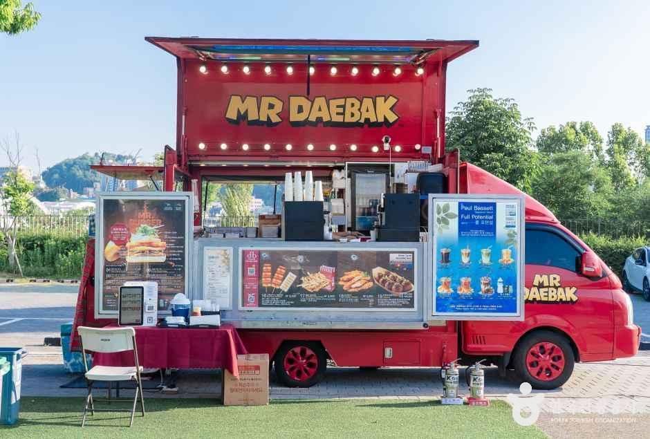 빨간 트럭 형태의 푸드트럭에서 샌드위치와 음료를 판매하는 노들섬 야외 공간