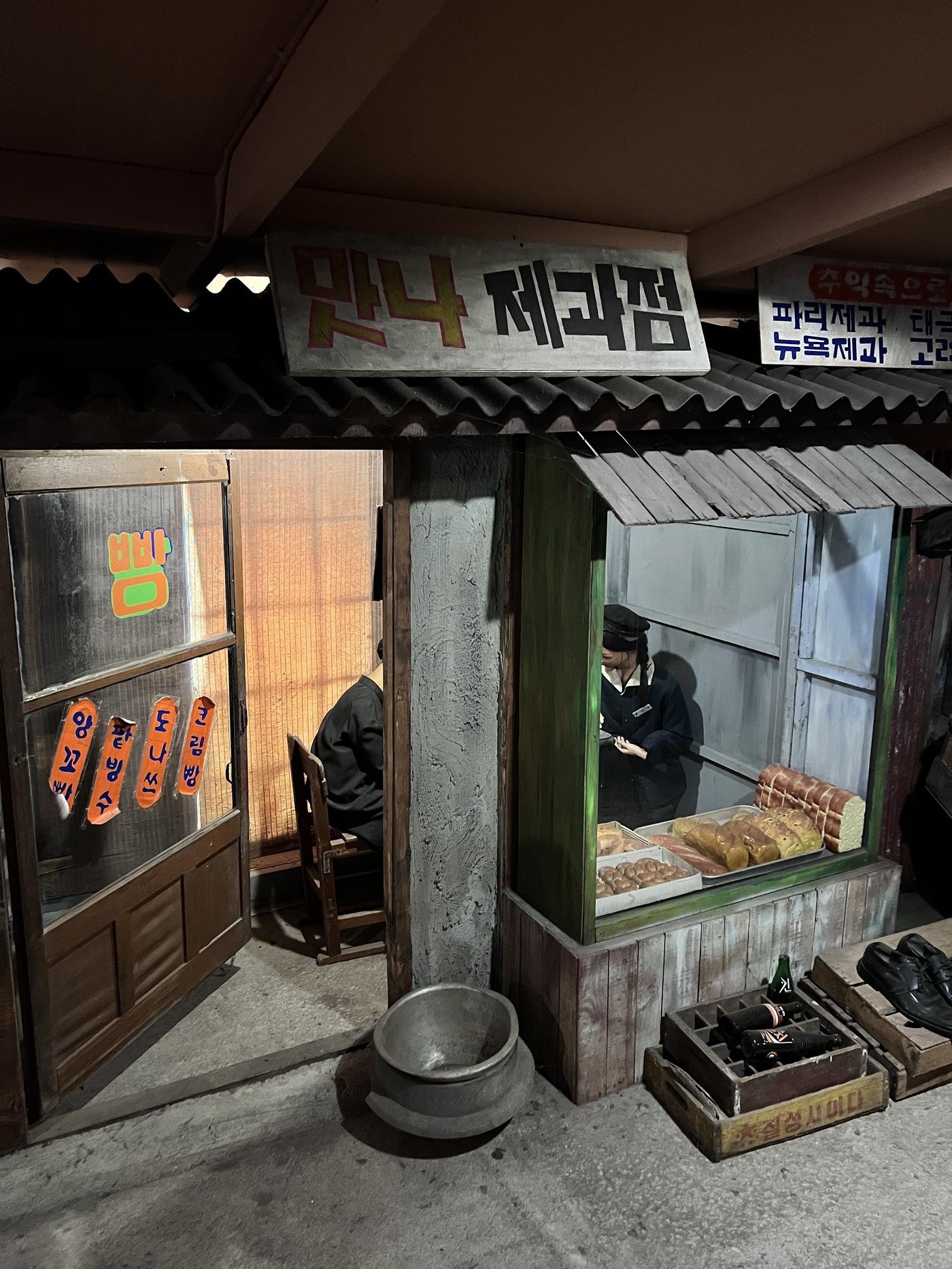맛나제과점 간판 아래 점원 마네킹과 빵 진열대