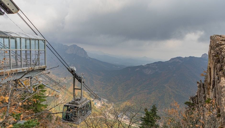 설악산 능선과 계곡 위로 케이블카 객차가 지나가는 풍경