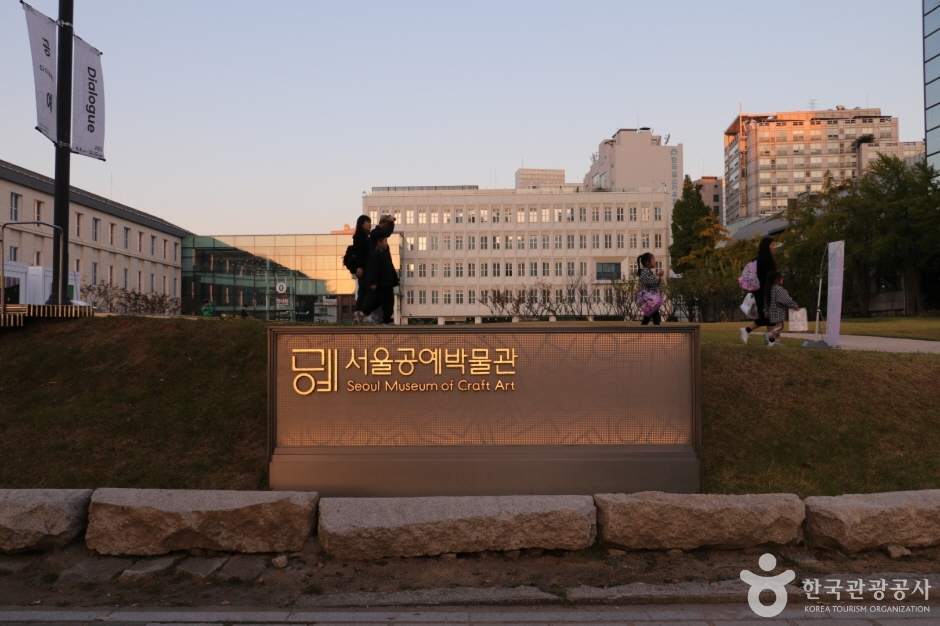 잔디 너머로 서울공예박물관 건물과 안내 표지가 보이는 야외 전경