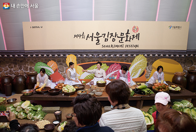 한복을 입은 참가자들이 무대 위에서 김장 담그기 시연을 하는 모습