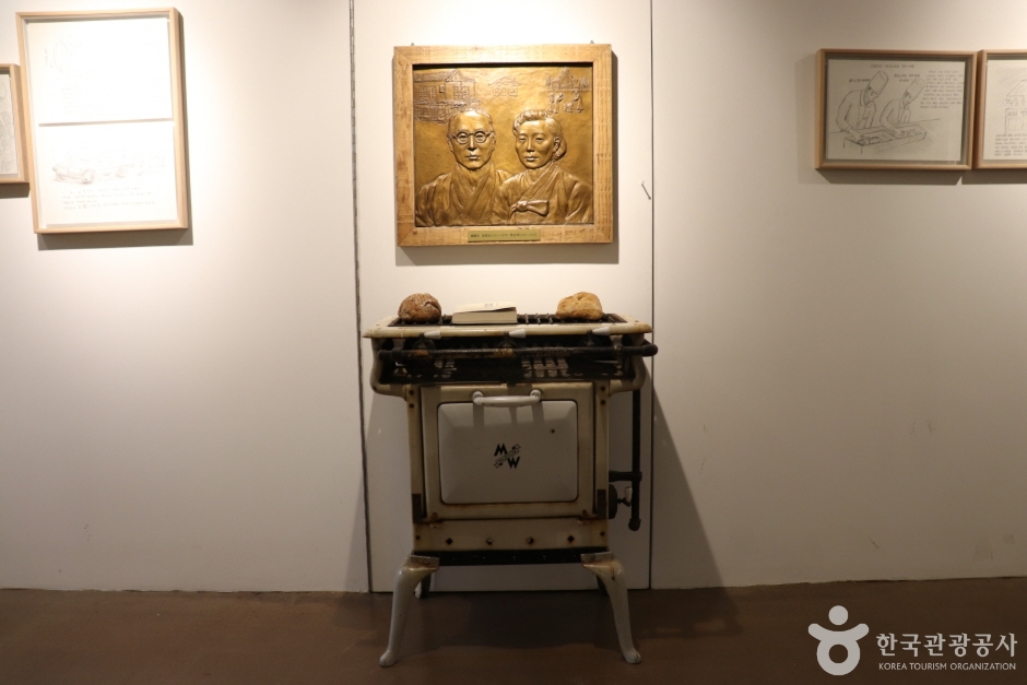 창업주 두 사람의 얼굴을 새긴 동판 부조와 그 아래 놓인 오래된 화덕형 오븐이 전시된 성심당문화원 전시 공간