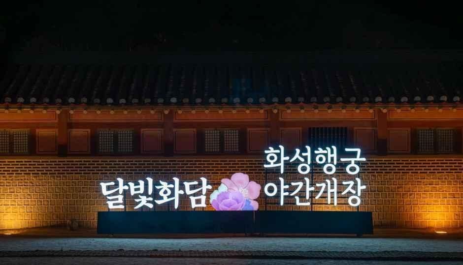 야간 개장을 알리는 달빛화담 화성행궁 글자가 붉은 벽 앞에 조명으로 비치는 모습