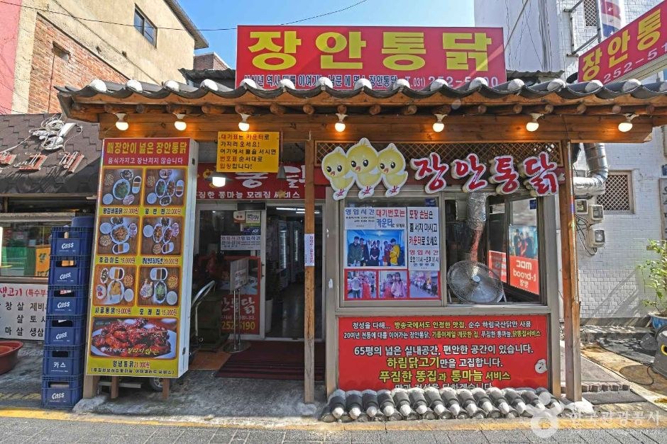 한옥풍 기와 처마 아래 장안통닭 간판이 붙은 오래된 통닭집 입구