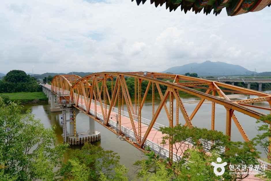 남강을 가로지르는 주황색 철교가 정암루 처마 아래로 길게 뻗어 있는 모습