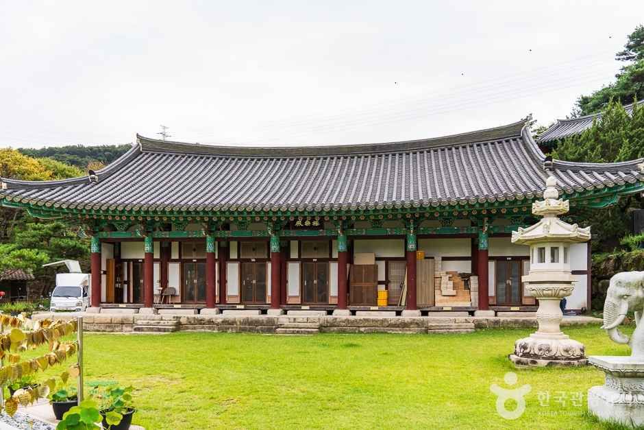 넓은 잔디마당 앞에 자리한 영평사 대웅전 기와지붕 전경, 마당 한쪽에 석등과 코끼리 조형물이 보이는 모습